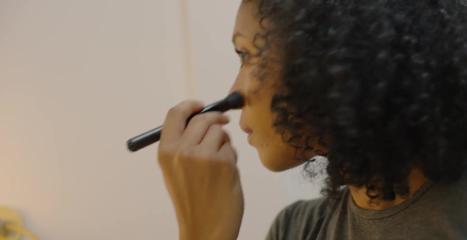 A woman brushes the makeup on and puts the brush down