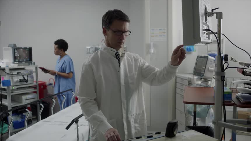 A doctor looking at a monitor as a woman takes notes on a clipboard