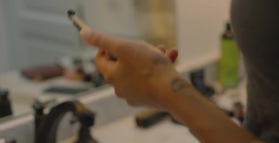 Woman applies makeup in front of a mirror in the bathroom
