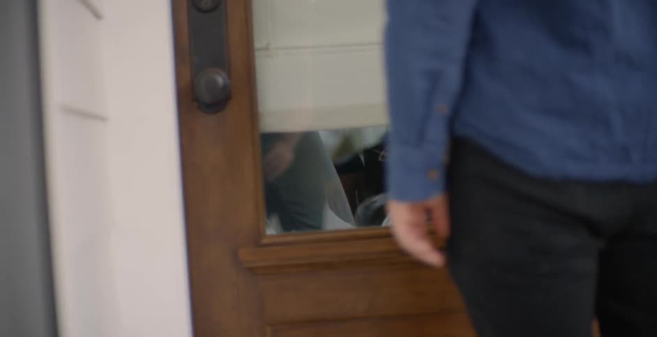 The woman opens the door holding the dog inside