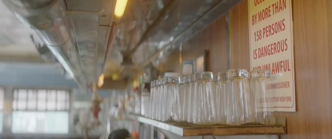 The diner has many glasses on the shelf