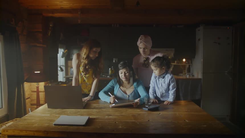 Three women and a child talk at the dining room table