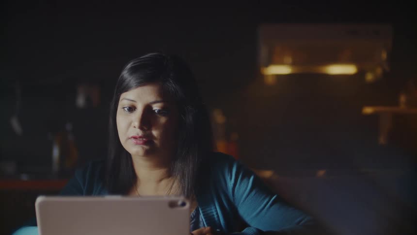 The woman uses her tablet and talks with someone