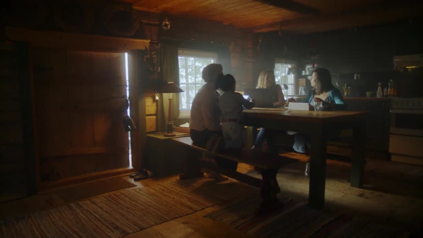 The women sit at the table talking with a child