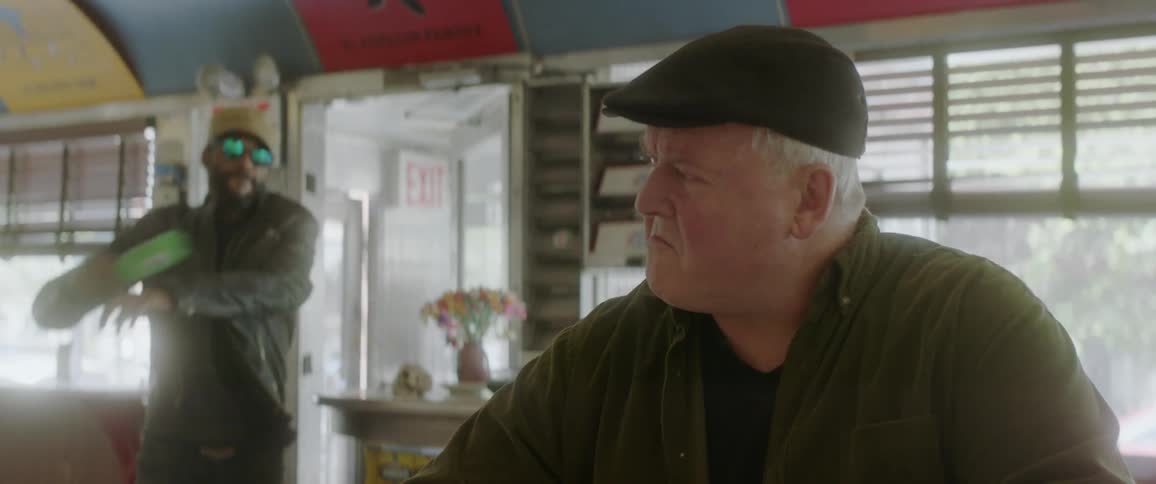 A man enters the diner and strikes a sitting person with a bottle