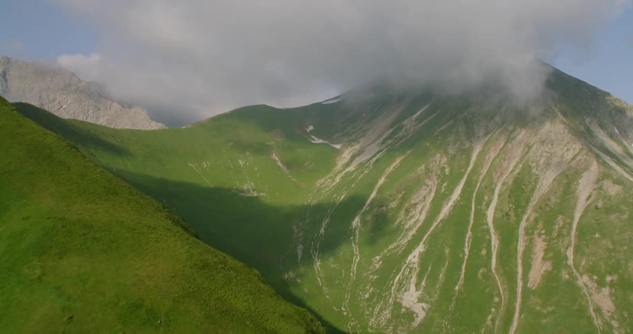 Clouds hang over the peaks of green peaks and slopes
