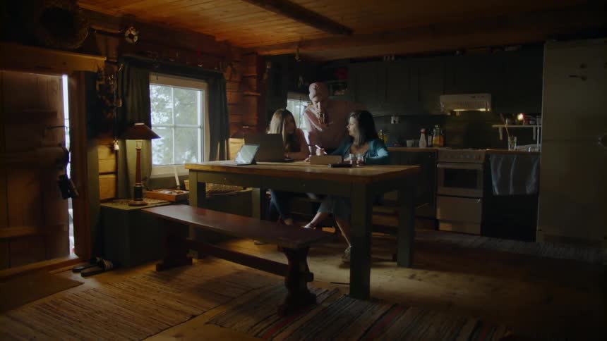 Several women sit at a table in a cabin with a child