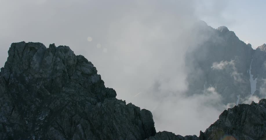 The large clouds are rolling over the ice covered mountains