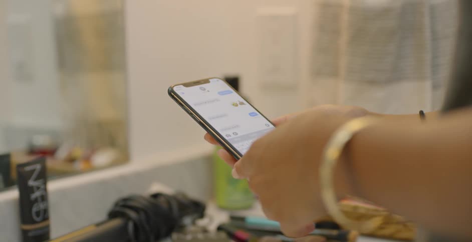 Woman is standing in bathroom looking at text feed on cell phone