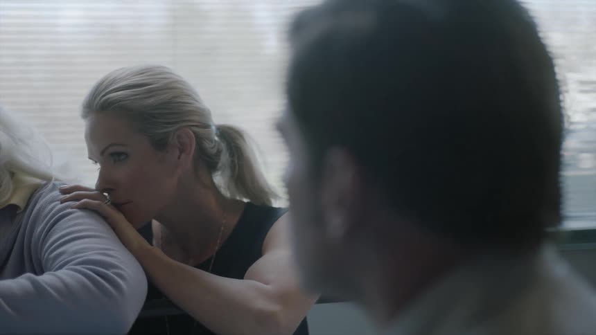 A woman comforts an older person while a man sits close