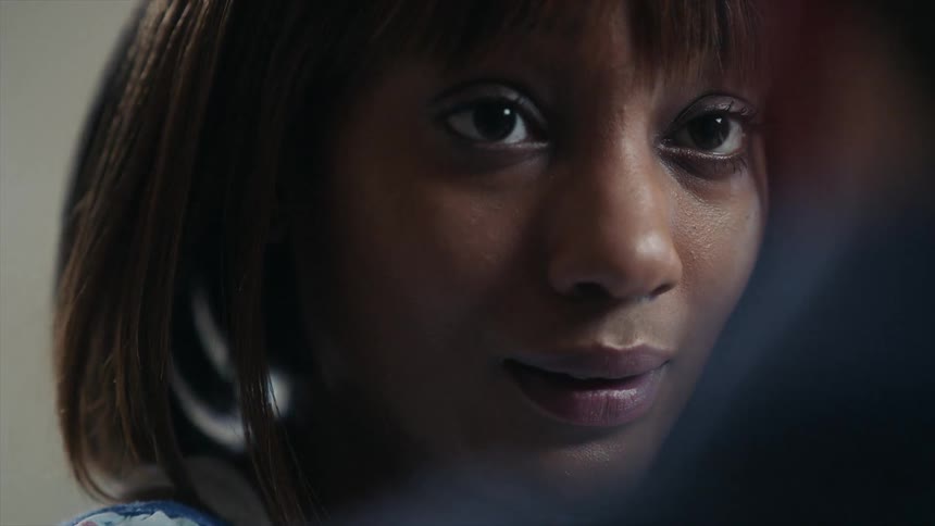 A black woman is shown in closeup looking at another person