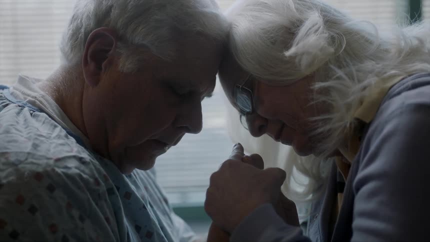 Elderly couple holding hands and comforting each other