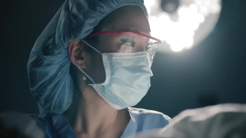 A doctor stands in front of a bright hospital light