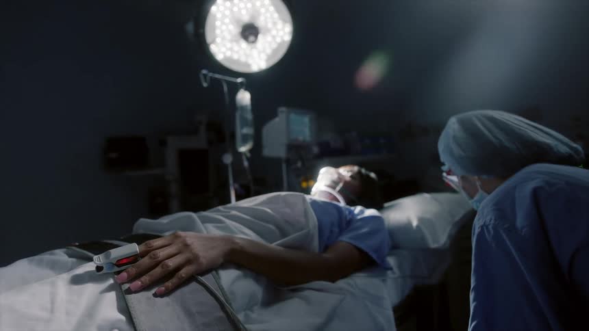 A nurse is adjusting the tubes for a patient in the bed