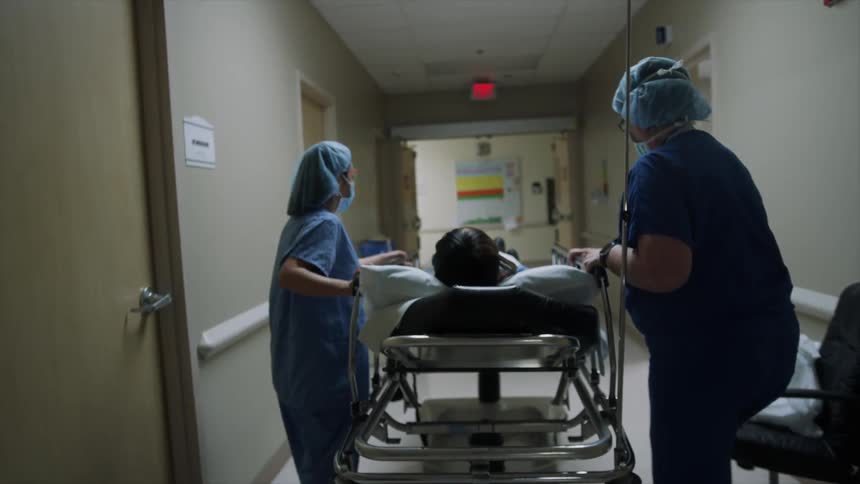 Two women wheeling a hospital bed down a hallway