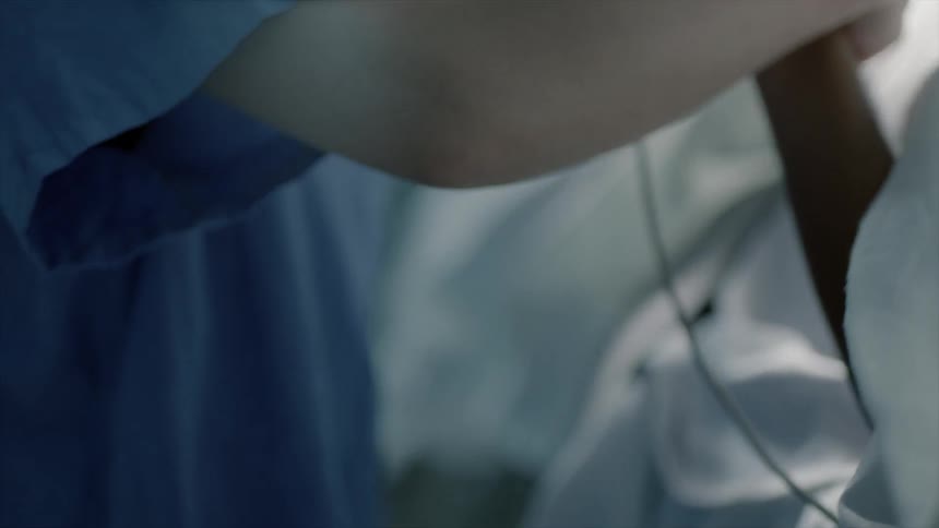 Nurse moving a patient's arm to cover it with a blanket