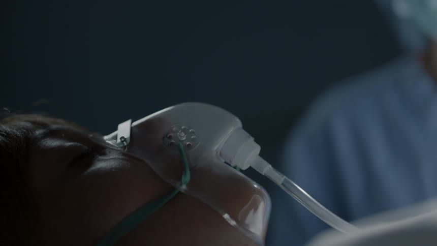 A doctor looks over a patient that is laying in a hospital bed