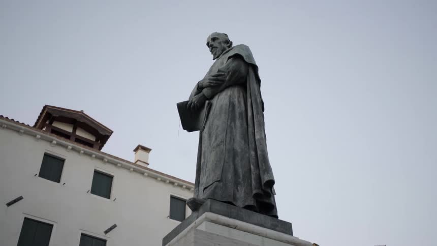 Statue of a religious man on a pedestal in front of a building