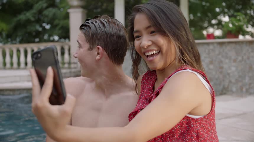 The woman splashes the man in the pool after a photograph