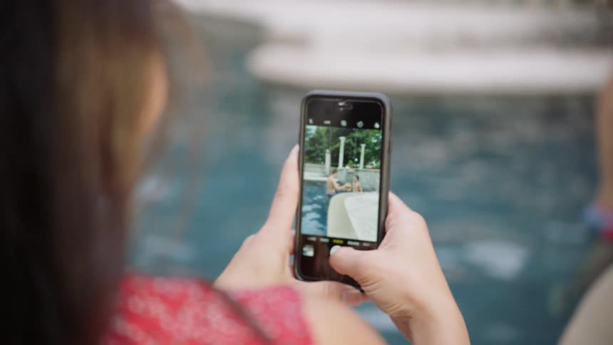 A woman is taking photographs of people inside the pool