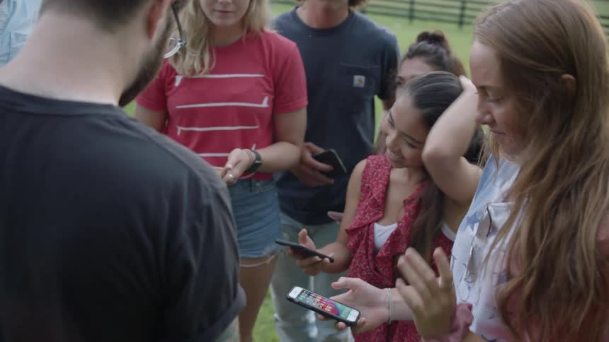 The people are standing together all holding cell phones