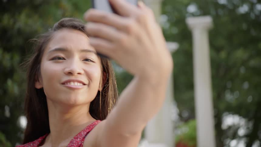 The woman is taking pictures of herself with her cell phone
