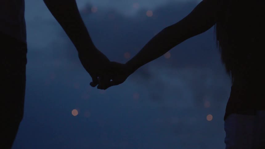 The two people hold hands as fireworks go off