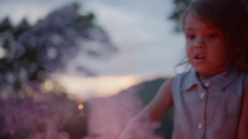 The child is waving a sparkler in front of her