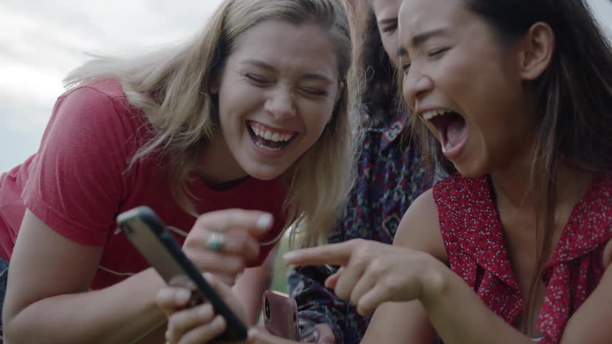 The women laugh together after looking at a cell phone