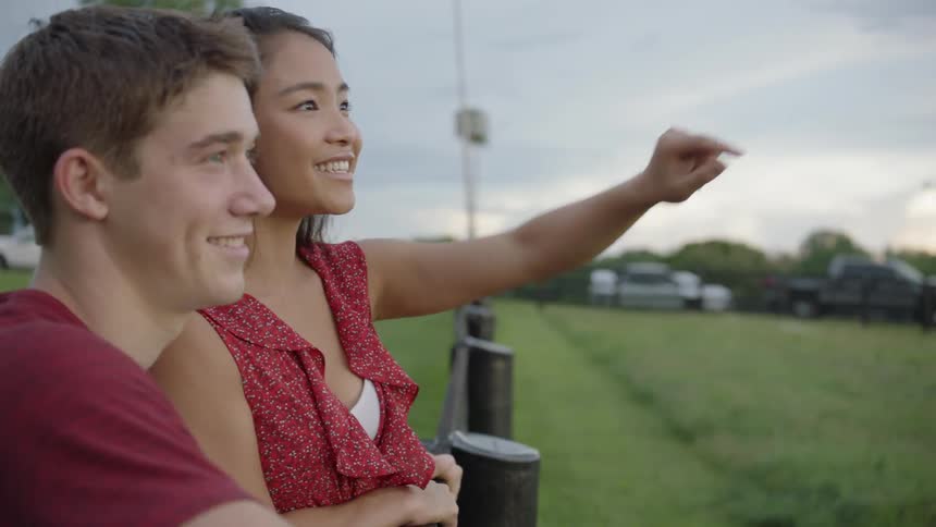 The man holds the woman as she points something out