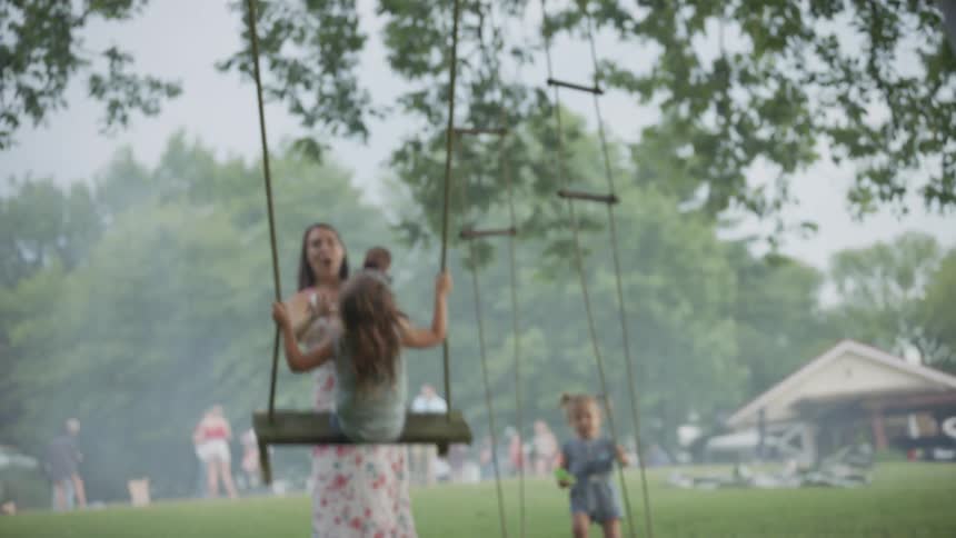 A family play in the yard on a swing