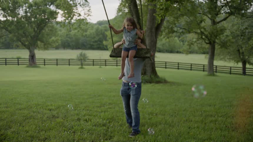 Father pushes young girl on swing
