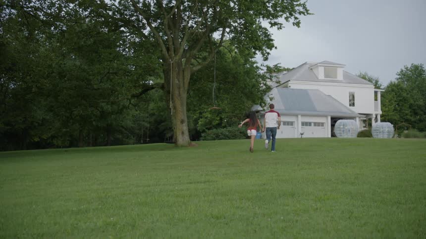 The man and woman run holding hands towards the house