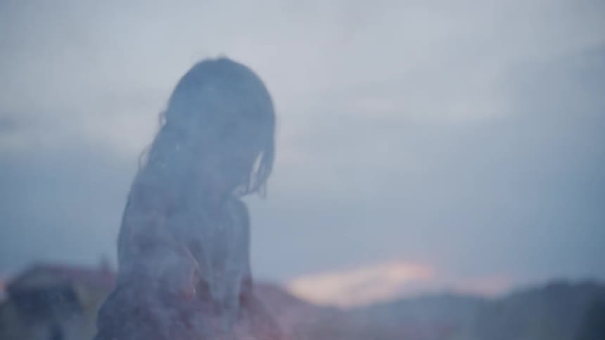 A little girl is holding a sparkler outside in a rural setting at dusk