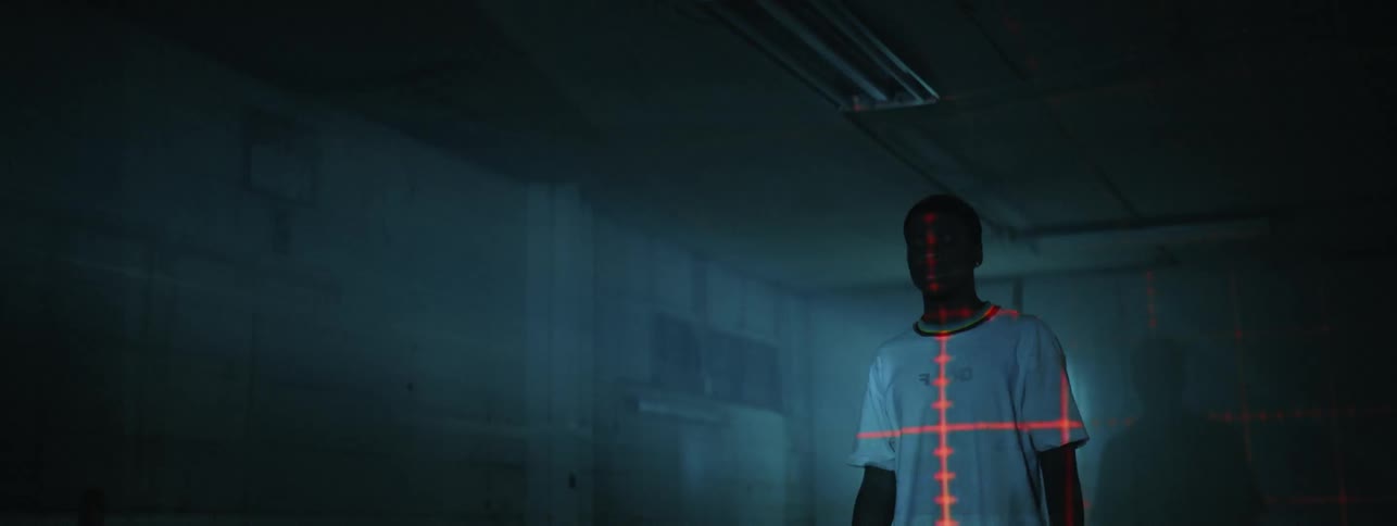 Man stands in a room with flashing lights and a red target on his shirt