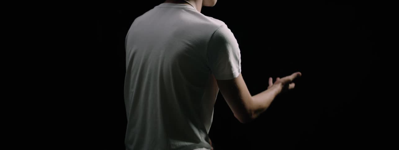 Man moving his hand in a dark room looking confused