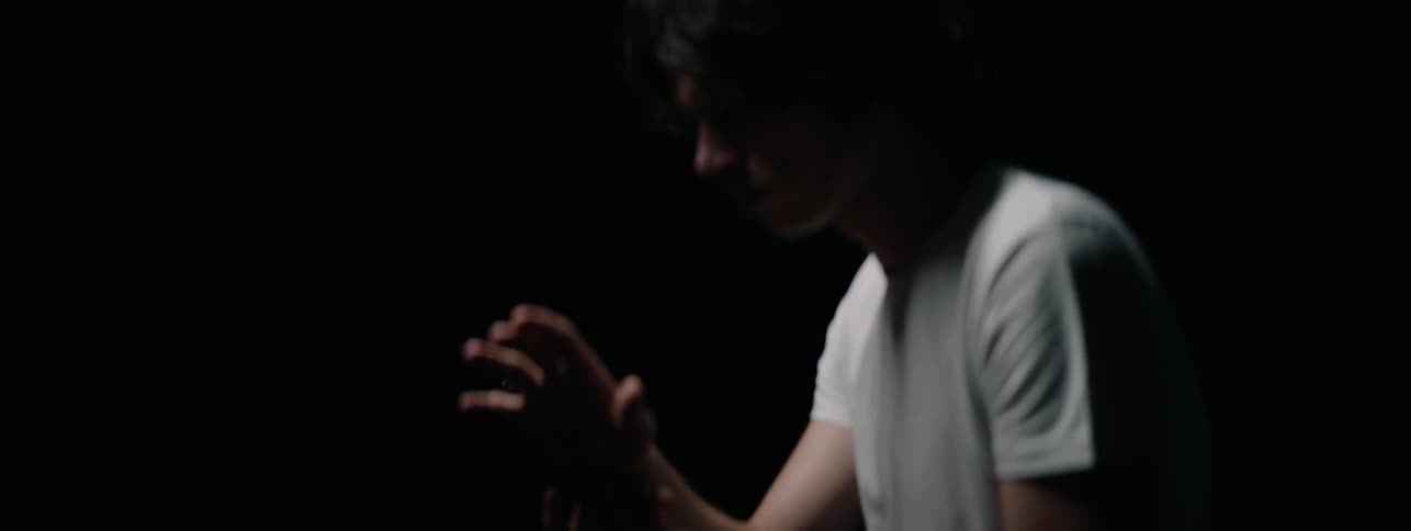 Man in a white shirt examines his hands as he moves them around