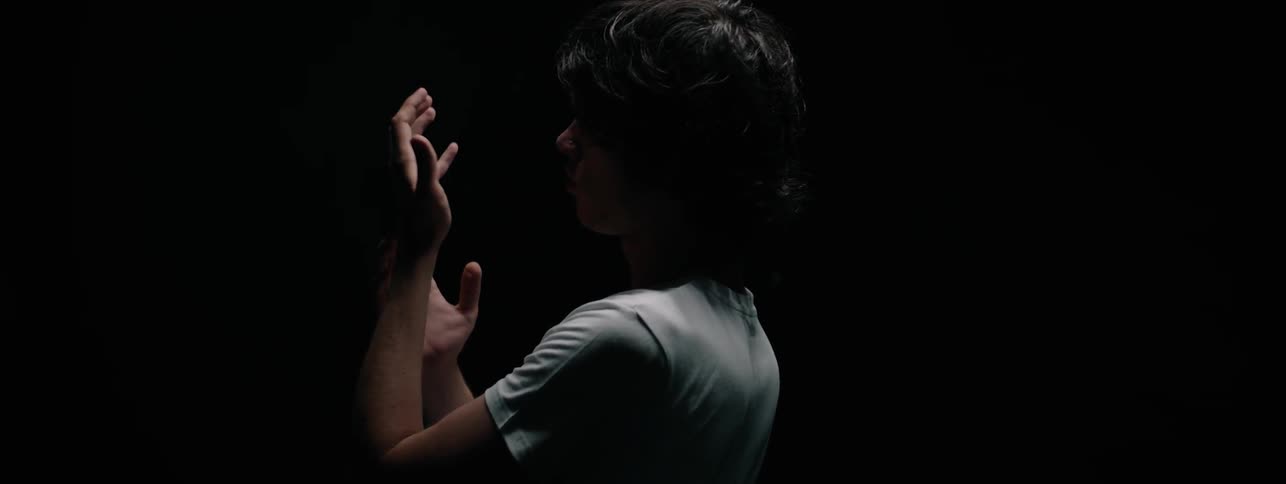 The man looks at his hands in the dark
