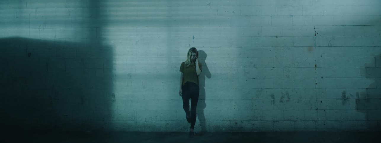 The woman leans against the brick wall