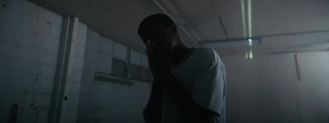 A boy stands in a room with hands on his face as light flashes and projects around him