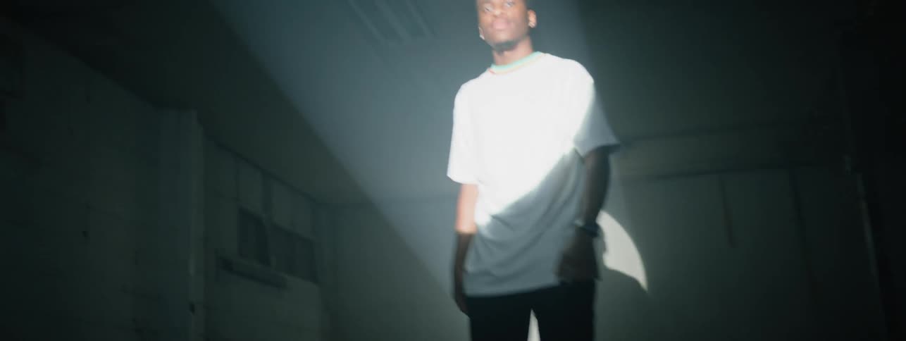 The man walks around in front of a strobe light in the dark room