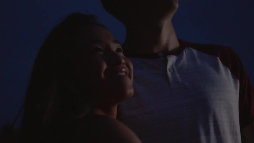 Smiling teenage boy and girl stand outside at night