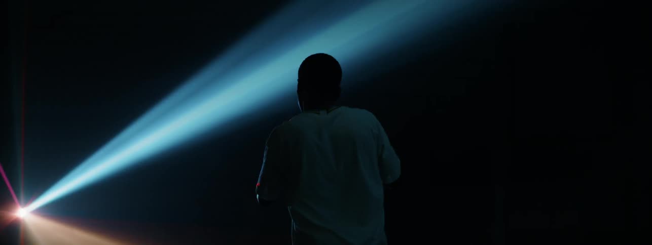 Man stands in a dark room illuminated by a flashing light