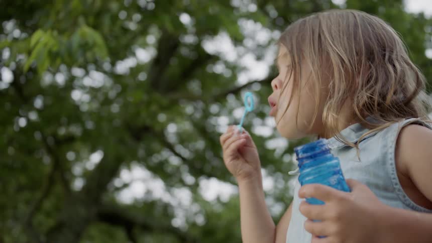 The girl is blowing bubbles on a cloudy day