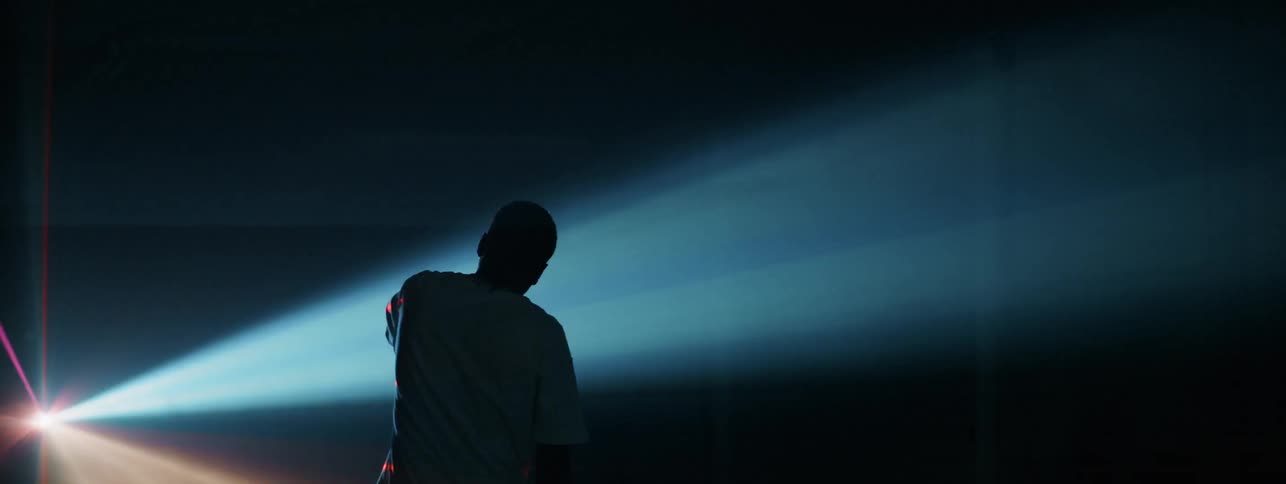 The man shields his eyes from the strobe lights