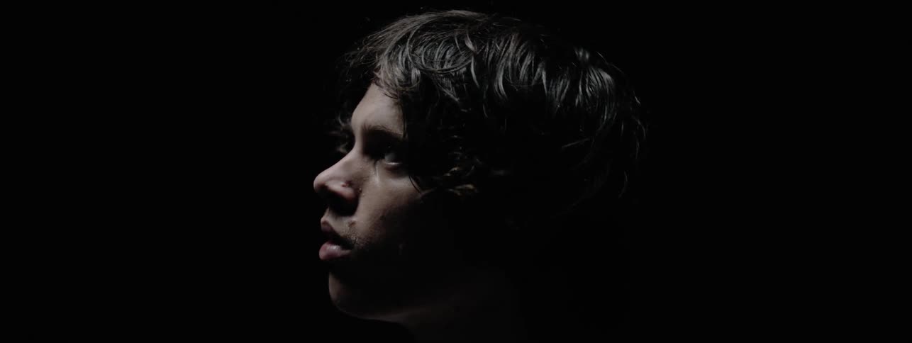 The man looks up slowly in the dark room