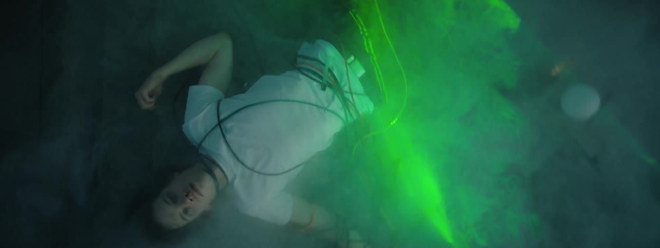 Smoke floats around a man bound in cables on a warehouse floor
