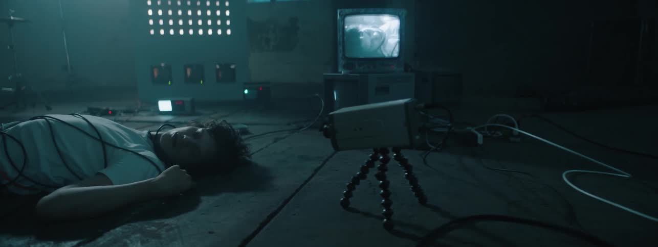The man lays on the floor covered in wires