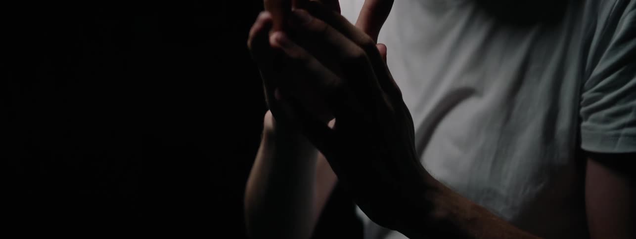 The man is waving his hand in the dark room