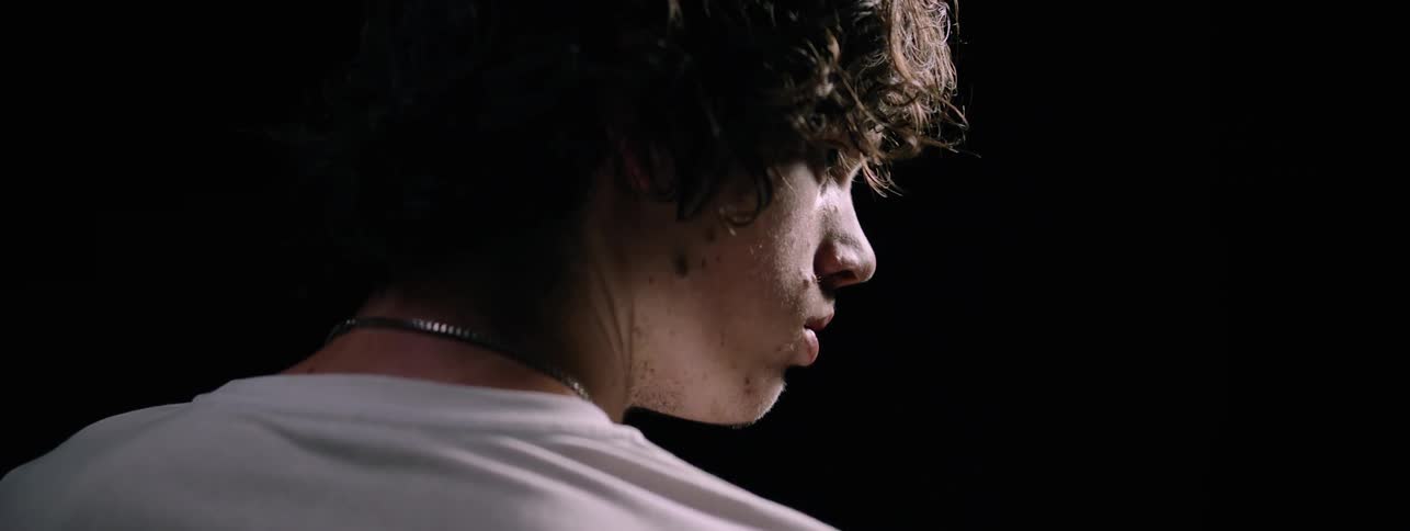The man looks to his side in the dark room